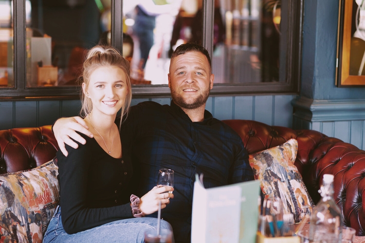 Couple enjoying drinks on a chesterfield sofa in the pub