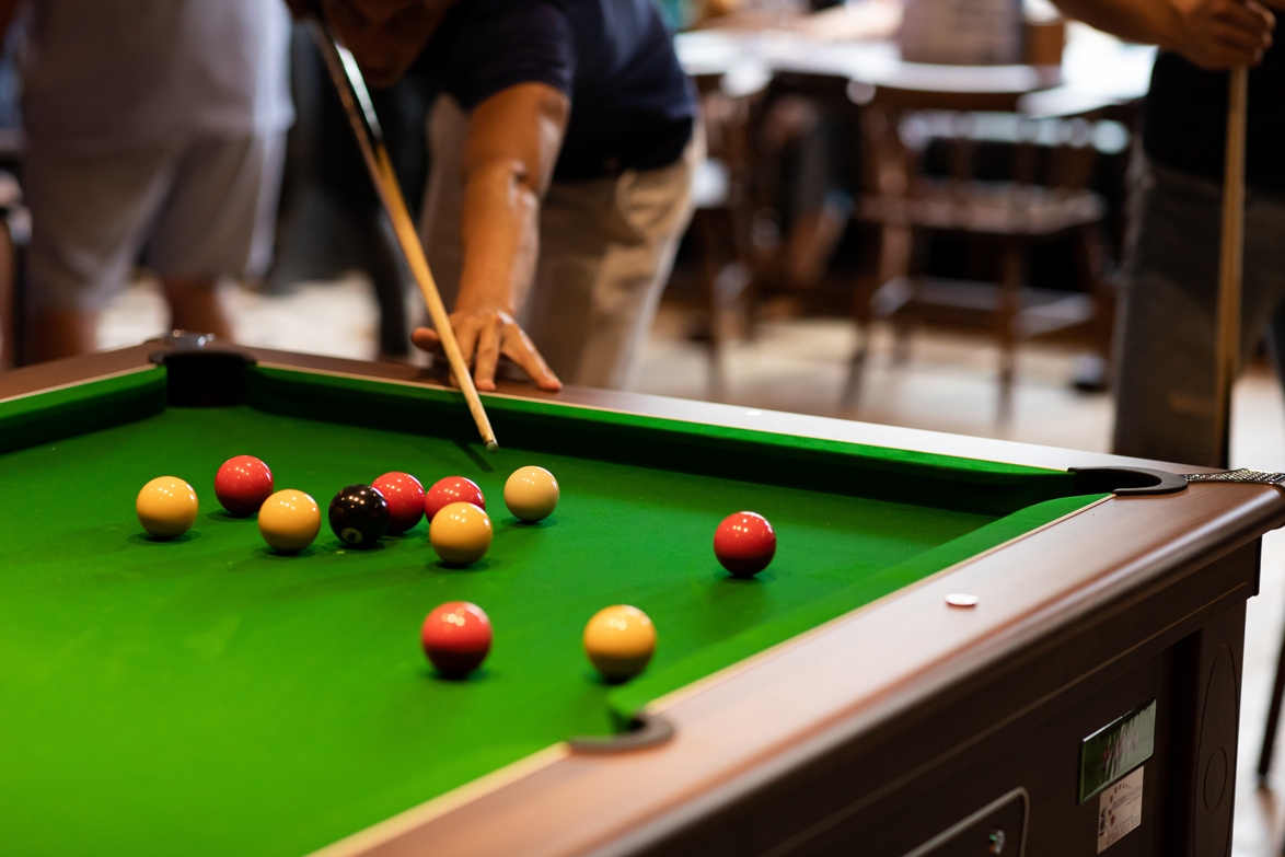 Friends playing pool on a green baize table in the pub