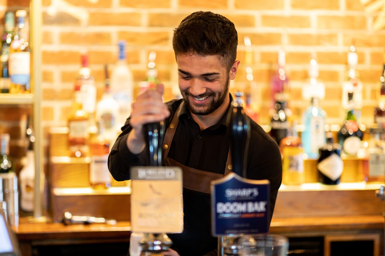 Bartender pouring a drink behind a pub bar